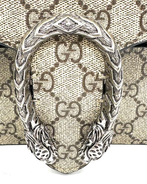 Bolso Dyonisus beige con estampado monogram y detalles de ante negro.